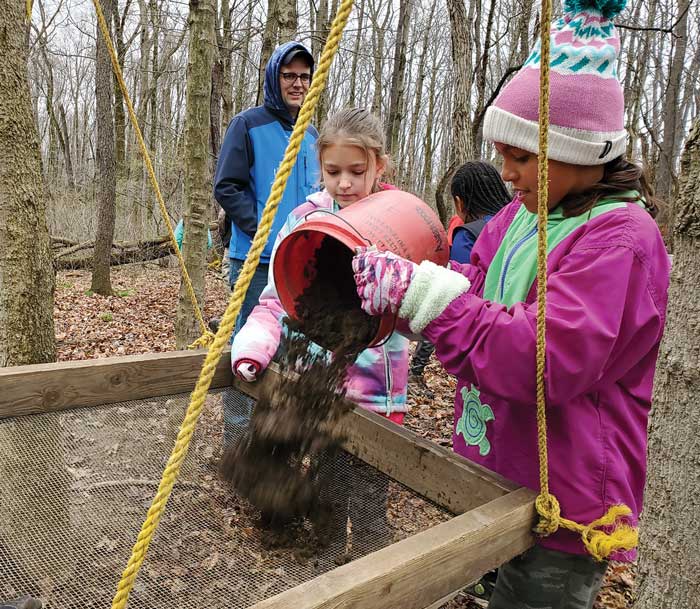 Students pouring dirt into sive